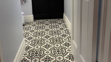 Une salle de bain avec un carrelage noir et blanc, une porte blanche et un miroir au-dessus du lavabo.