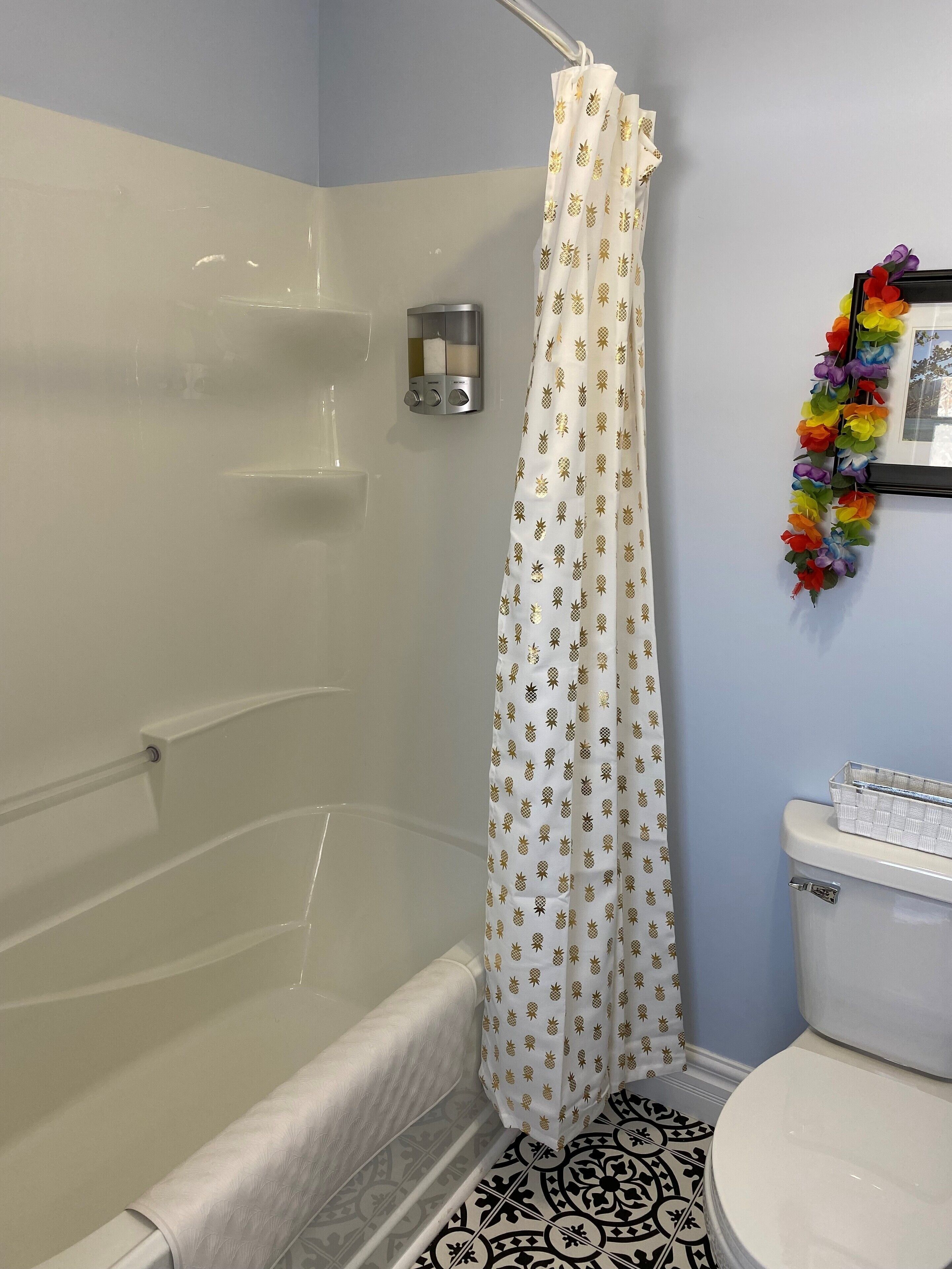 A bathroom with a bathtub, toilet, and shower curtain with a pineapple pattern.