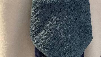 A folded towel with a textured pattern, placed on a white surface.