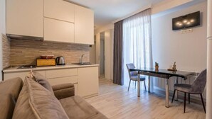 Eine moderne Wohnung mit einer Küchenzeile, einem Essbereich mit Glastisch und einem Wohnzimmer mit Sofa.
