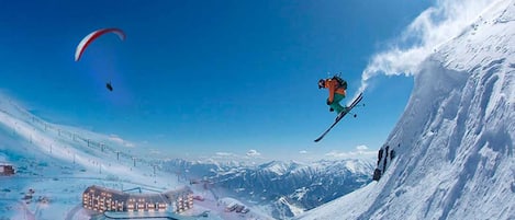A ski resort with a large building, ski slopes, and a person skiing.