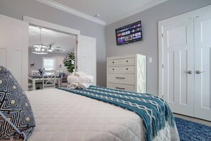 Ein Schlafzimmer mit Bett, Wandfernseher, Schreibtisch mit Stuhl und Kleiderschrank.