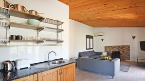 A modern kitchen with wooden cabinets, a black countertop, and stainless steel appliances. There is a gray sofa and a fireplace in the living area. - Villa Ses Costes with private pool, garden and panoramic views of the mountains in Alaró  (Alaro)