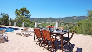 An outdoor patio with a pool, dining table, and chairs, overlooking a mountainous landscape. - Villa Ses Costes with private pool, garden and panoramic views of the mountains in Alaró  (Alaro)