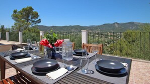 An outdoor dining area with a table set for four, overlooking a scenic view of hills and vineyards. - Villa Ses Costes with private pool, garden and panoramic views of the mountains in Alaró  (Alaro)