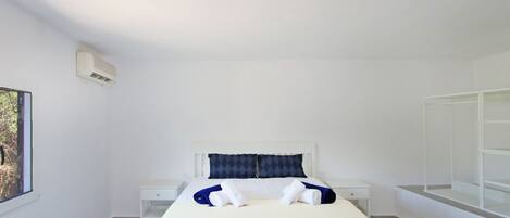A clean, modern hotel room with a bed, two nightstands, a window, and a built-in wardrobe.