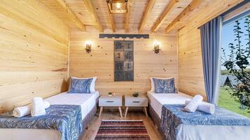 Una habitación tipo cabaña de madera con dos camas, una mesita pequeña y dos luces fijadas a la pared.
