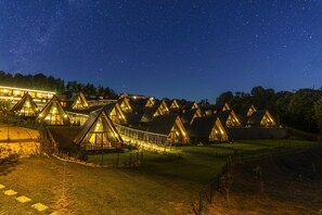 A row of triangular-roofed cabins with a glass bridge connecting them, set against a starry night sky. - Aronia Bungalow (Yalova)