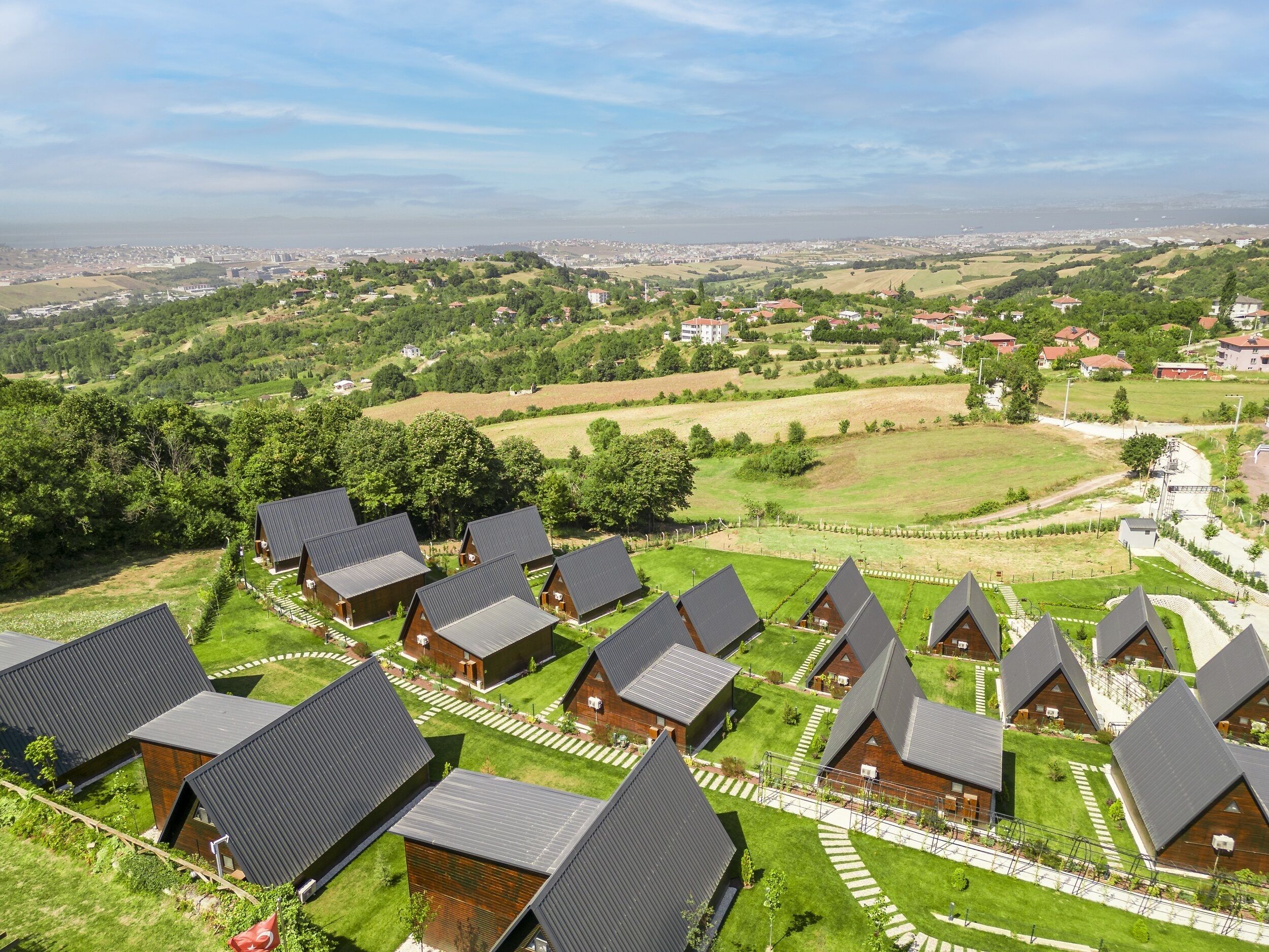 Um conjunto de cabanas modernas, com telhados triangulares, um gramado bem cuidado e vista ampla da paisagem ao redor.