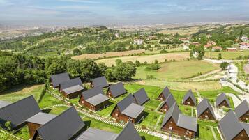 Um conjunto de cabanas modernas, com telhados triangulares, um gramado bem cuidado e vista ampla da paisagem ao redor.