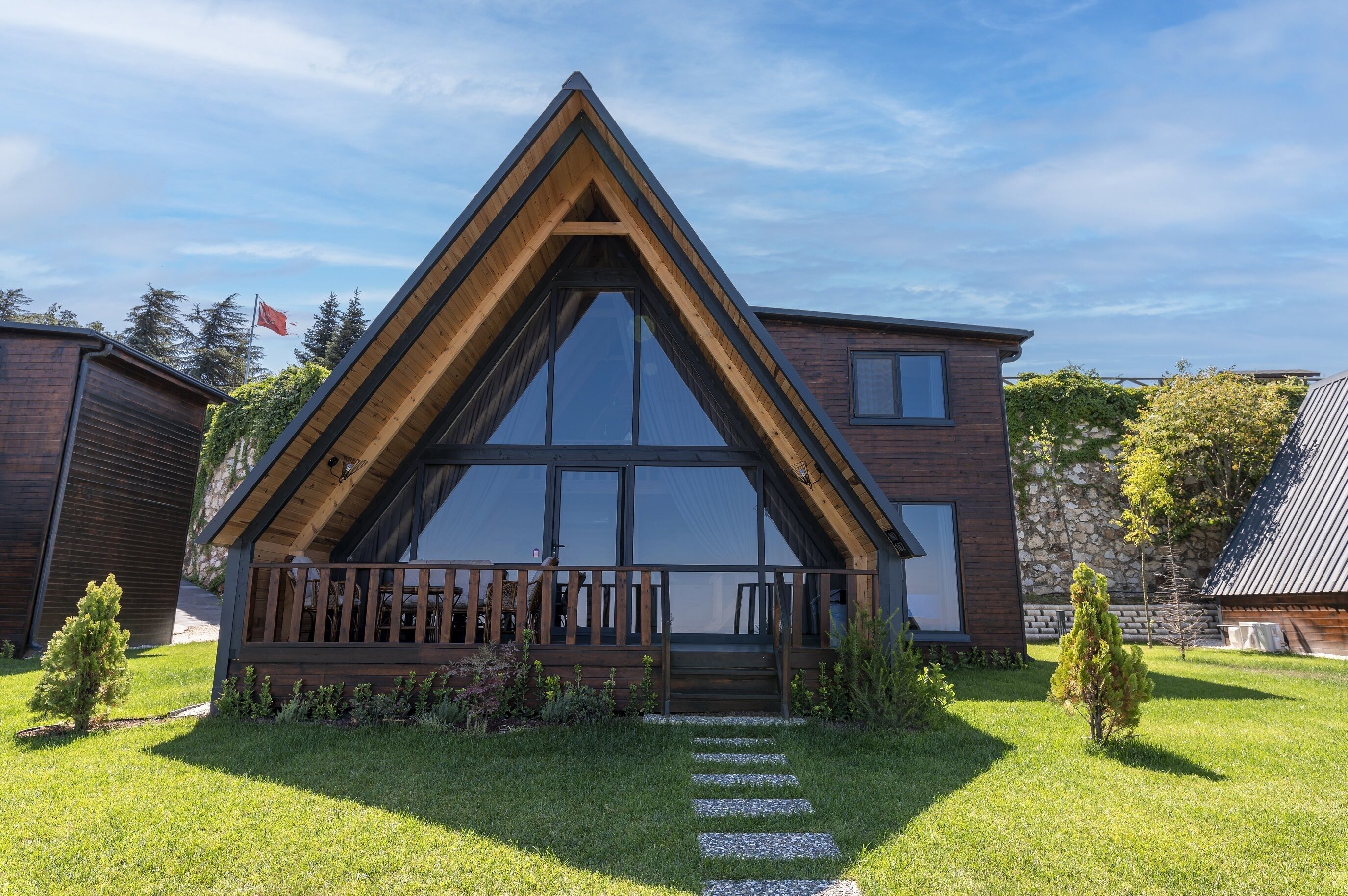 Una casa moderna con techo triangular, ventanas amplias y una terraza de madera.