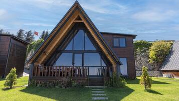 Una casa moderna con techo triangular, ventanas amplias y una terraza de madera.