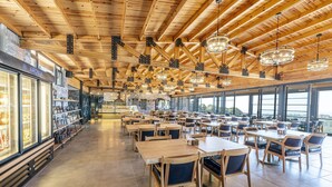 Un ampli restaurant amb bigues de fusta, grans finestres i diferents opcions de seients.