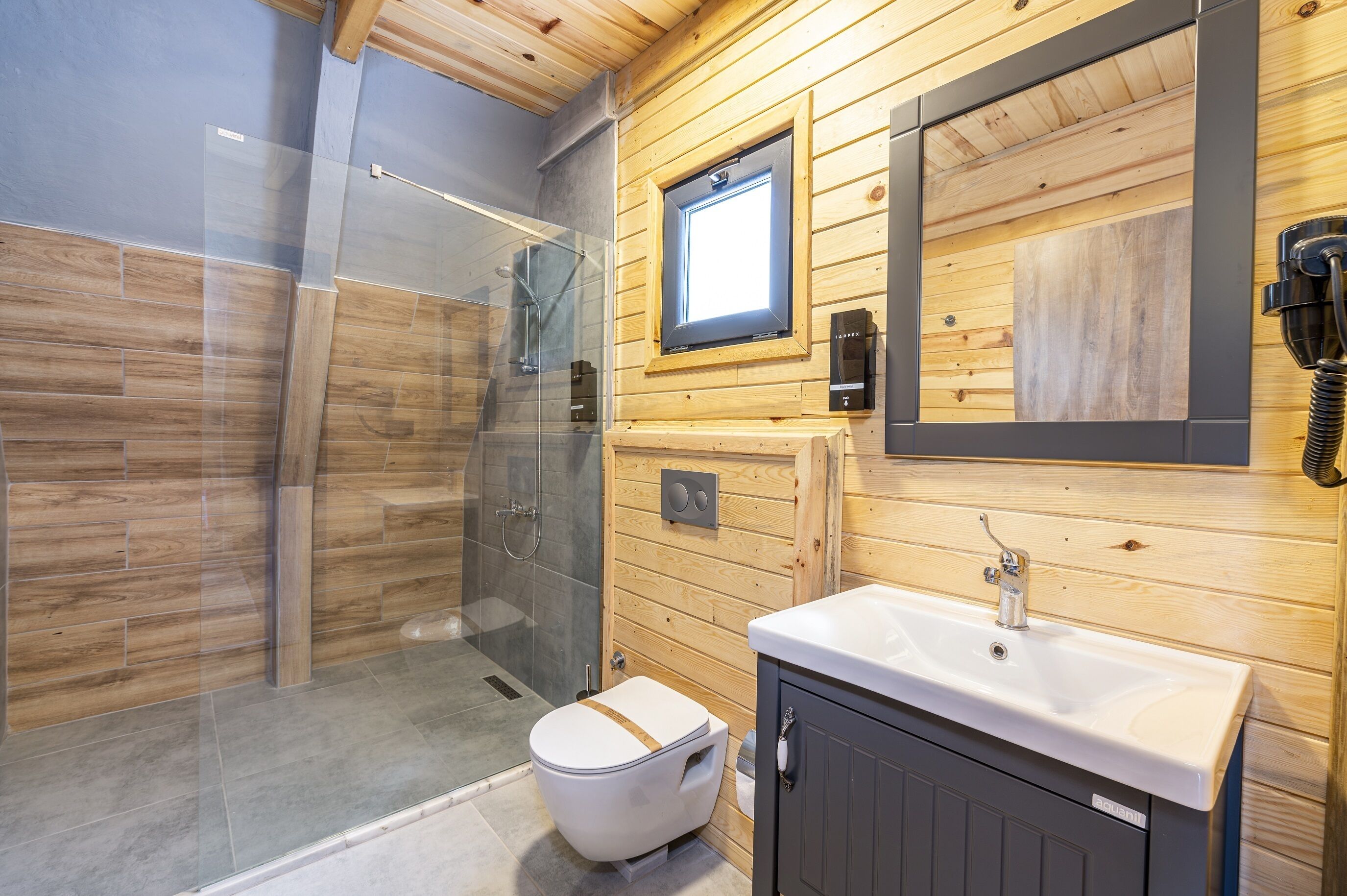 Un baño moderno con cabina de ducha de vidrio, tocador de madera y un espejo grande.
