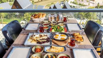 Un tavolo apparecchiato con diversi piatti, tra cui pane, uova e frutta, su un balcone con vista sulla città.