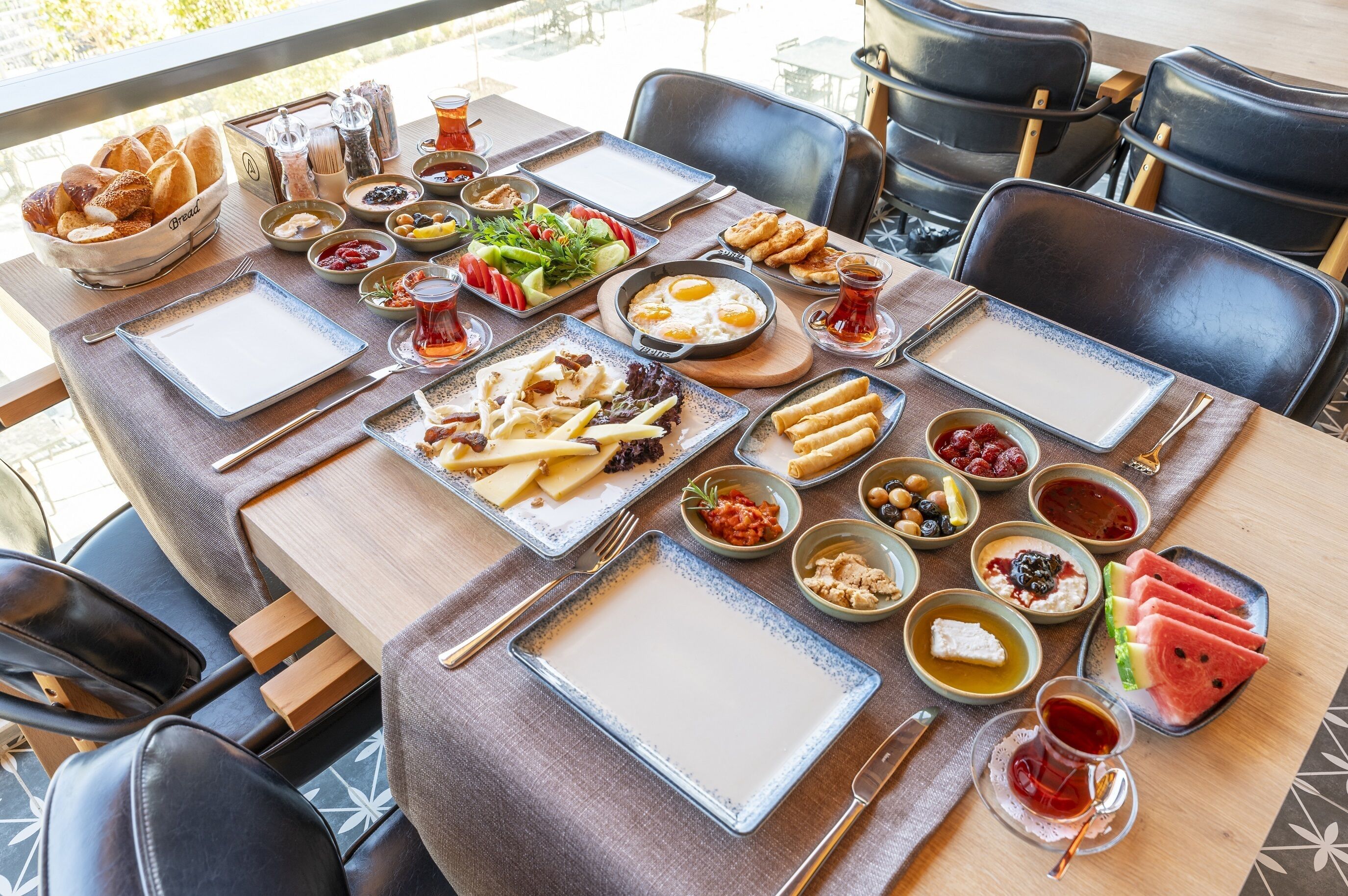 A table set with various dishes including bread, salads, and fruits, suggesting a sit-down meal in a restaurant.