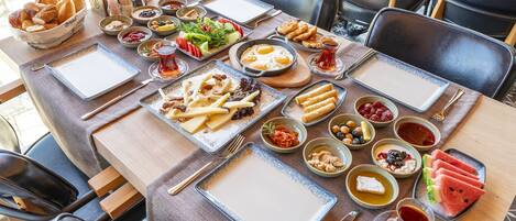 A table set with various dishes including bread, salads, and fruits, suggesting a sit-down meal in a restaurant.