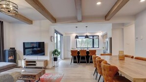 A modern living room with a fireplace, TV, and dining area with wooden furniture.
