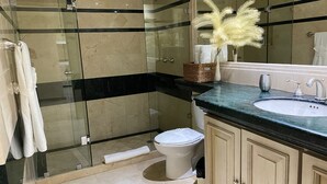 Un bagno moderno con cabina doccia in vetro, un water bianco e un lavabo con piano in marmo.