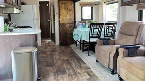 A compact RV interior with a kitchenette, dining area, and seating. - The Lazy Turtle Inn + Beach & Pool (Key Largo)