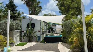 A caravan with a covered patio area, surrounded by tropical vegetation and a clear sky. - The Lazy Turtle Inn + Beach & Pool (Key Largo)