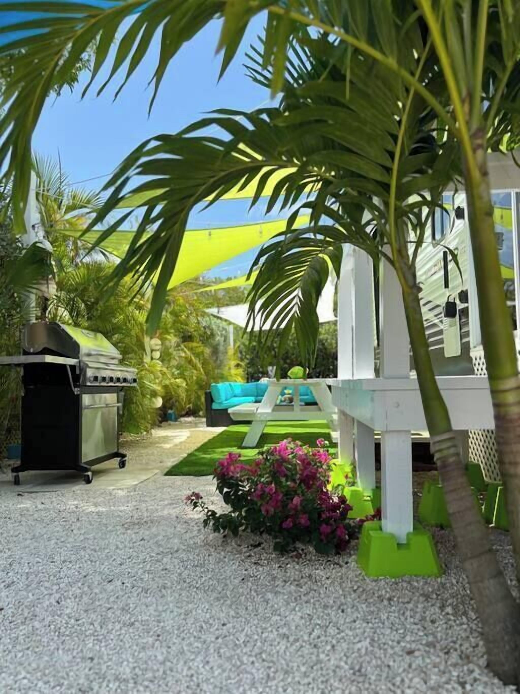 A patio area with a grill, outdoor furniture, and a small garden with pink flowers.