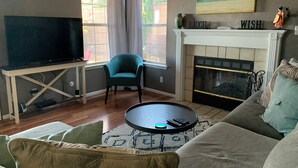 A living room with a TV, a fireplace, a sofa, and a chair. - 3 Bed Desert Beach House with a Mountain View - Private Pool and Hot Tub! (Rio Rancho)