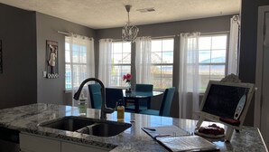 A kitchen with a marble countertop, a sink, a dining area with a table and chairs, and a chalkboard sign. - 3 Bed Desert Beach House with a Mountain View - Private Pool and Hot Tub! (Rio Rancho)