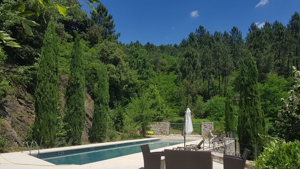 A swimming pool with lounge chairs and a stone wall, surrounded by dense forest. - Cevennes Nature Entourée de Végétation, à 3mn de la Rivière, à 1mn de la Piscine (Chambon)