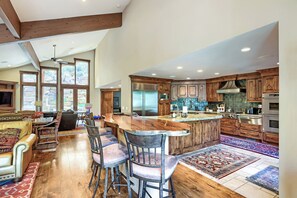 A spacious kitchen with wooden cabinets, a large island, and a dining area with leather chairs.