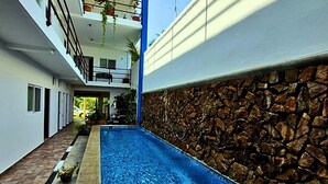 A swimming pool with a stone wall on one side and a building with balconies on the other. - blue Bocana Hotel (Santa María Huatulco)
