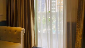Ein Zimmer mit einer Couch und einem Fenster mit durchsichtigen Vorhängen.