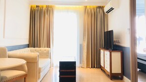 Ein Hotelzimmer mit einer Couch, einem kleinen Tisch, einem Fernseher auf einem Schrank und einem Koffer.