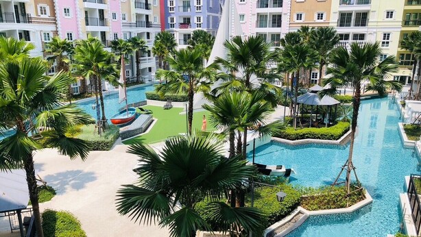 Ein Resort mit mehreren Swimmingpools, Palmen und einem mehrstöckigen Gebäude im Hintergrund.