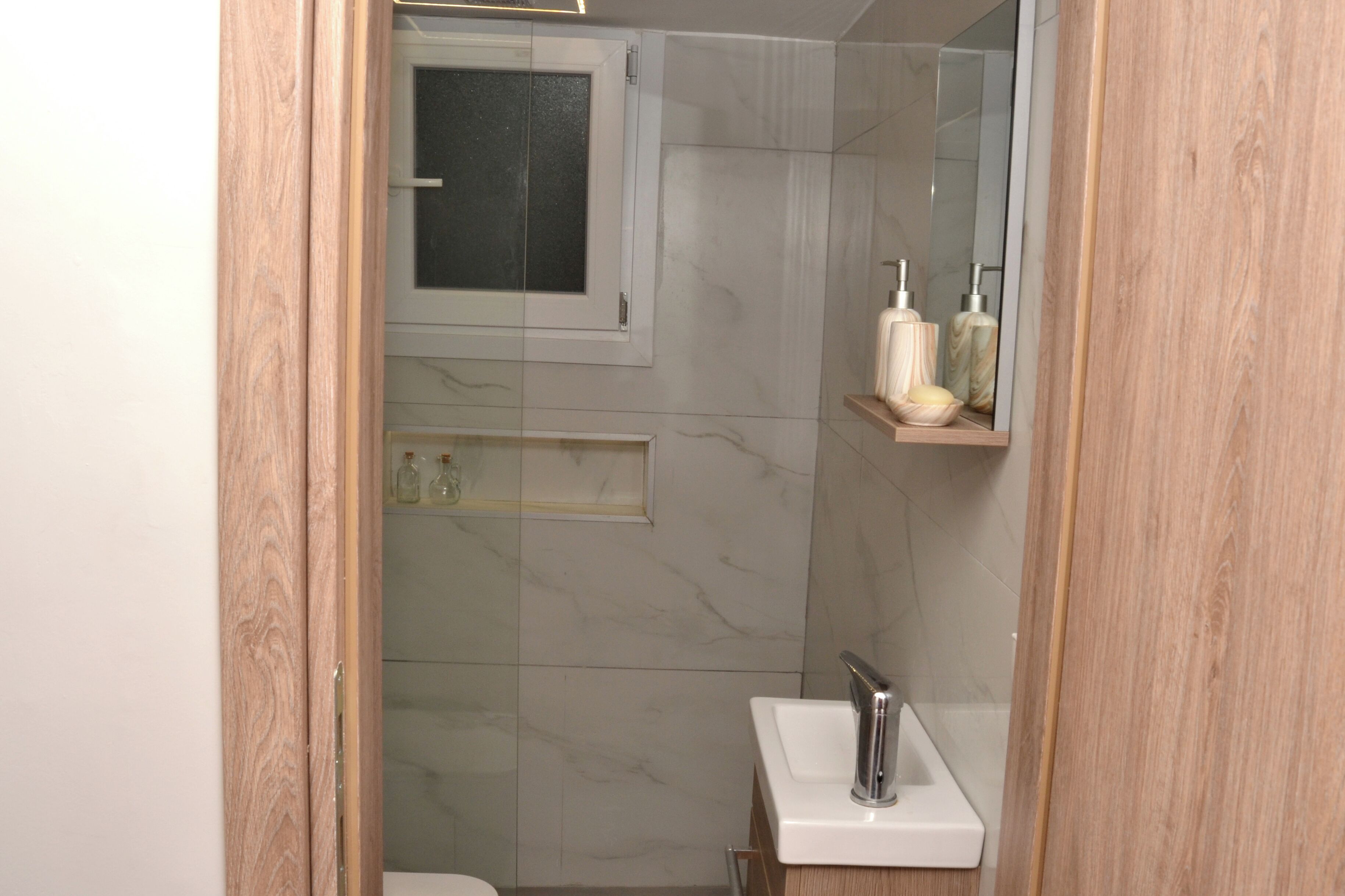A bathroom with a glass shower enclosure, a white sink, and a mirror above the sink.