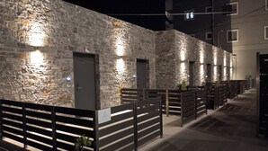 A stone building with multiple doors and windows, a gated entrance, and a potted plant. - EcoHeaven Suites (Malevizi)