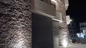 A modern building with a stone facade and illuminated entryway. - EcoHeaven Suites (Malevizi)