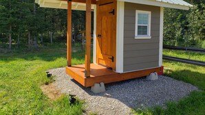 A small wooden cabin with a metal roof, a single door, and a window. - Glamping tent close to the river by Sundre, Alberta (James River Bridge)