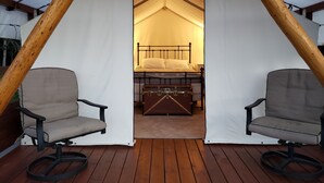 A tent with a bed, two chairs, and a chest of drawers. - Glamping tent close to the river by Sundre, Alberta (James River Bridge)