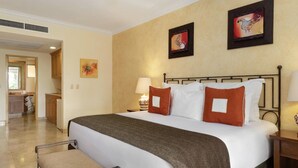 A hotel room with a bed, two bedside tables with lamps, a headboard, and artwork on the walls. - Villa del Arco  Beach Front. Grocery store on site or short ride. Full Kitchen.  (Cabo San Lucas)