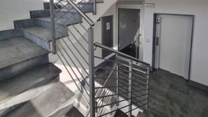 Ein modernes Interieur mit einer Treppe, die zu einer oberen Etage führt, einer Tür und einer Wandleuchte.