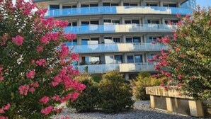 Ein mehrstöckiges Hotel mit Balkonen, umgeben von Grünpflanzen und Blumen.