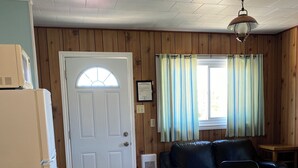A compact kitchen with a white refrigerator, stove, and a wooden dining table with a remote control. - Jackfish Lake Cottages Motel (Unorganized Thunder Bay District)