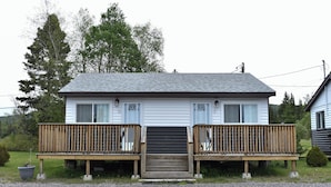 A two-story house with a front porch, a garage door, and a small front yard. - Jackfish Lake Cottages Motel (Unorganized Thunder Bay District)