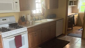 Una cocina con armarios de madera, una estufa blanca, un microondas y un lavamanos.