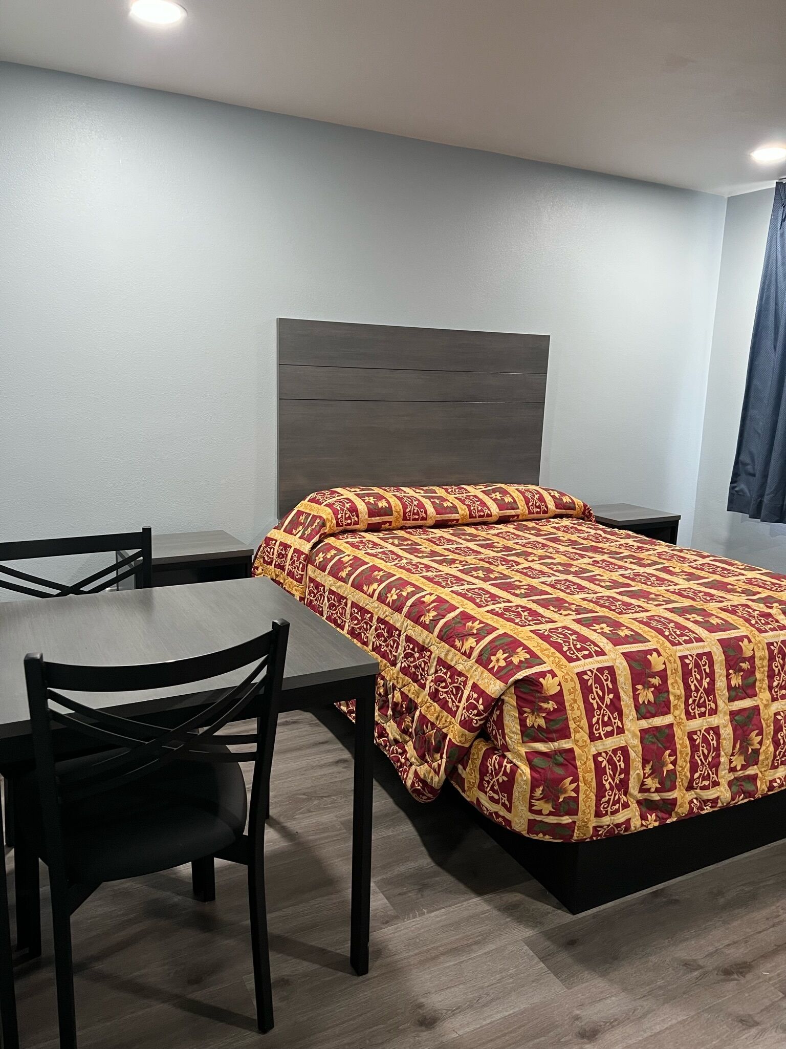 A hotel room with a bed, a table, and two chairs.