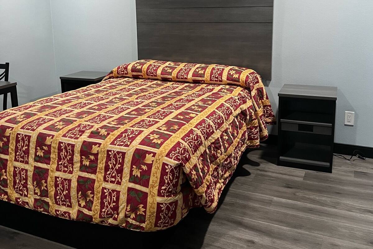 A bedroom with a large bed, a nightstand, and a dresser.