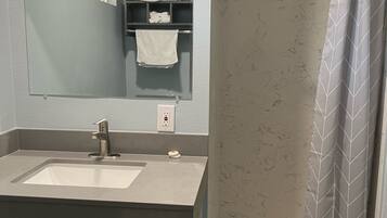 A bathroom with a sink, mirror, towel rack, and shower curtain.