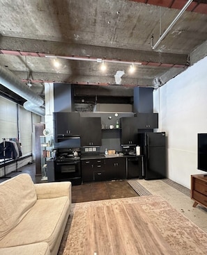 A compact living space with a kitchenette, a sofa, and a television. - The Continental Royal Loft (Los Angeles)