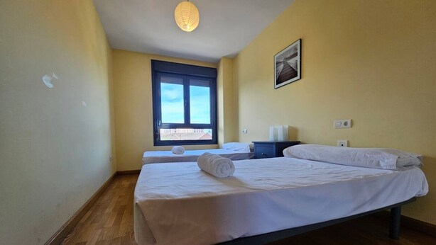 Un dormitorio con una cama, una ventana, una mesita de noche y un cuadro colgado en la pared.